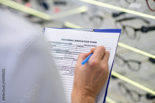 Close up of ophthalmologist filling universal medical form