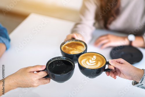 Closeup image of people enjoyed drinking and clinking coffee cups on the table in cafe