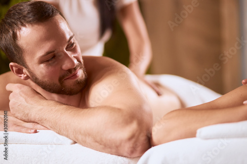 Handsome young man with stylish beard turning hand towards female partner, talking with interest, receiving hand massage, having pleasure, total relaxation concept
