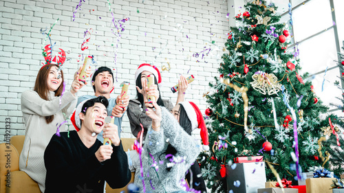 Asian people party celebrate christmas and new year eve in house and christmas tree decorate with confetti paper shoot
