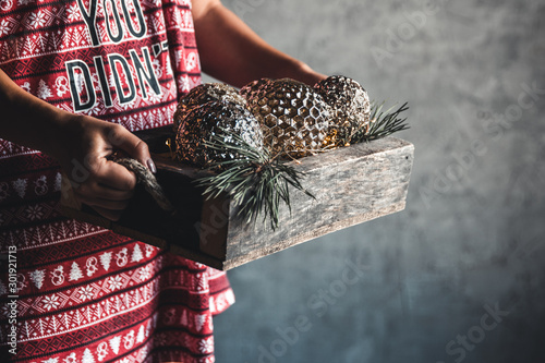 Girl in a Christmas dress holds balls in a wooden box, holiday, comfort
