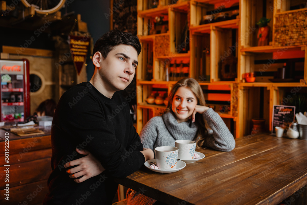 a young couple hugs in a cafe and drinks coffee a young couple hugs in a cafe and drinks coffee
