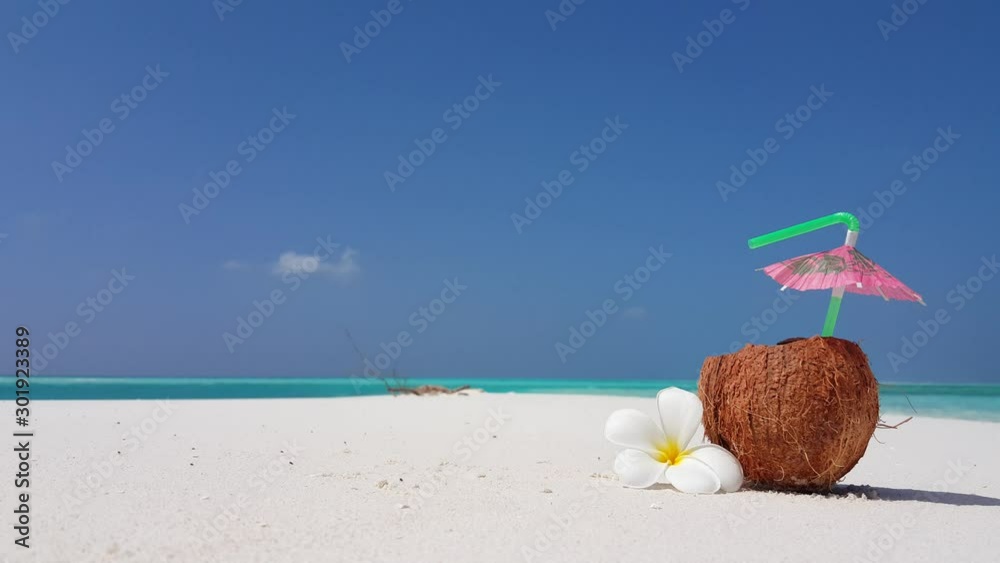 Coconut drink on a tropical white sand beach, ocean lagoon straw with a small umbrella Coconut drink on a tropical white sand beach, ocean lagoon straw with a small umbrella