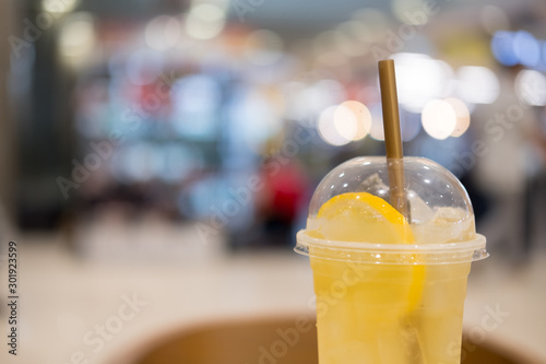 Iced tea mix with lemonade with lemons and gold straw in takeaway tall glass