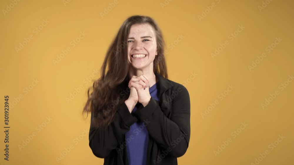 Happy woman joyfully clapping her hands against a yellow background Happy woman joyfully clapping her hands against a yellow background