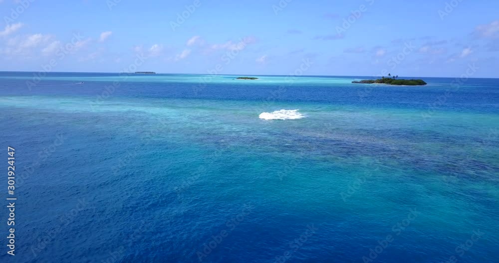White wave appearing from blue azure lagoon splashing over coral reef, tropical islands of Indonesian archipelago White wave appearing from blue azure lagoon splashing over coral reef, tropical islands of Indonesian archipelago