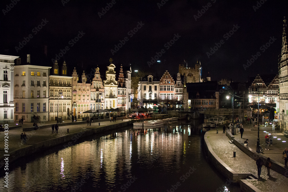 Ghent, Belgium; 10/27/2019: Most famous canal in Ghent, Belgium, with reflections of the illuminated typical belgian houses on the water during the night, through Leie river (Lys river)