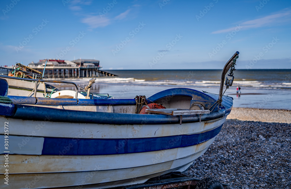 21 Traditional crab fishing boat in focus with an out of focus sea, pier and beach in the background