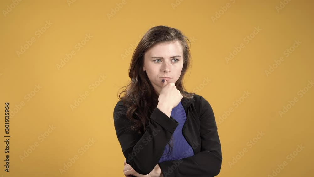 Pensive young woman against yellow background Pensive young woman against yellow background