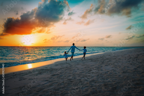 happy father with son and daughter play on sunset beach