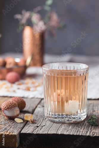 Glass of cold lychee juice on the old wooden table, rustic style