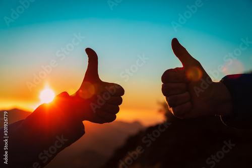 father and son thumb up in sunset mountains