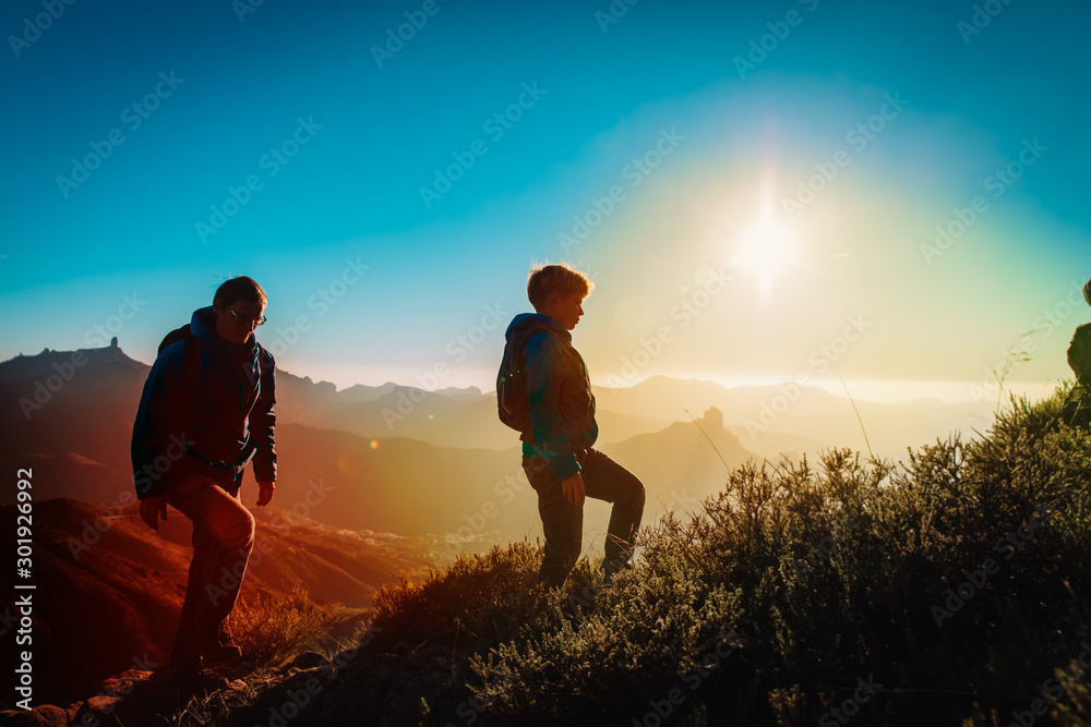 father and son hiking in sunset mountains, family travel