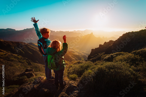 happy boy and girl travel in mountains at sunset