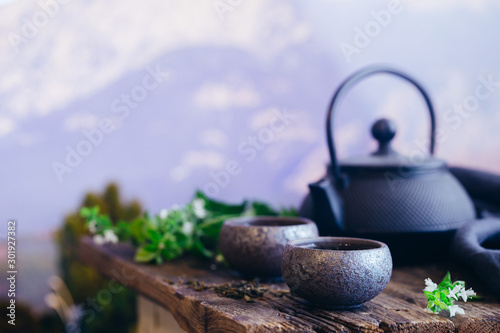 Two cups of green tea and teapot on wooden table and nature background with copy space