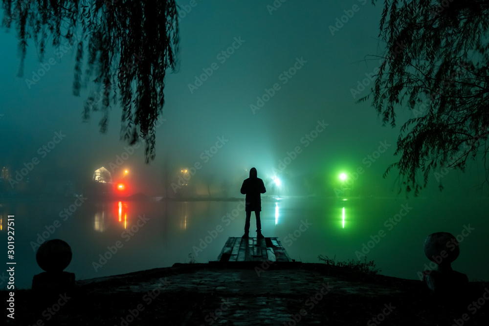 Fototapeta premium silhouette of a man and a lake in the fog at night