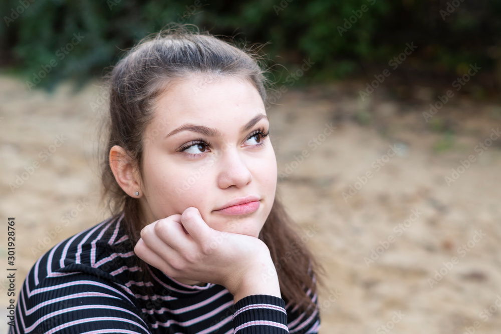 Confident and cheerful young woman looking away with her head resting on her hand Confident and cheerful young woman looking away with her head resting on her hand