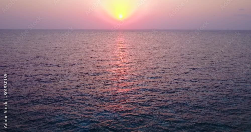 Beautiful sunset with yellow sun on pink sky reflecting sunlight over endless dark ocean, copy space Beautiful sunset with yellow sun on pink sky reflecting sunlight over endless dark ocean, copy space