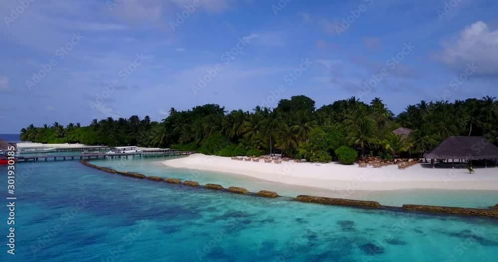 Luxurious resort on Maldivian tropical island with wide white beach, sunbeds, wooden bridge and big restaurant