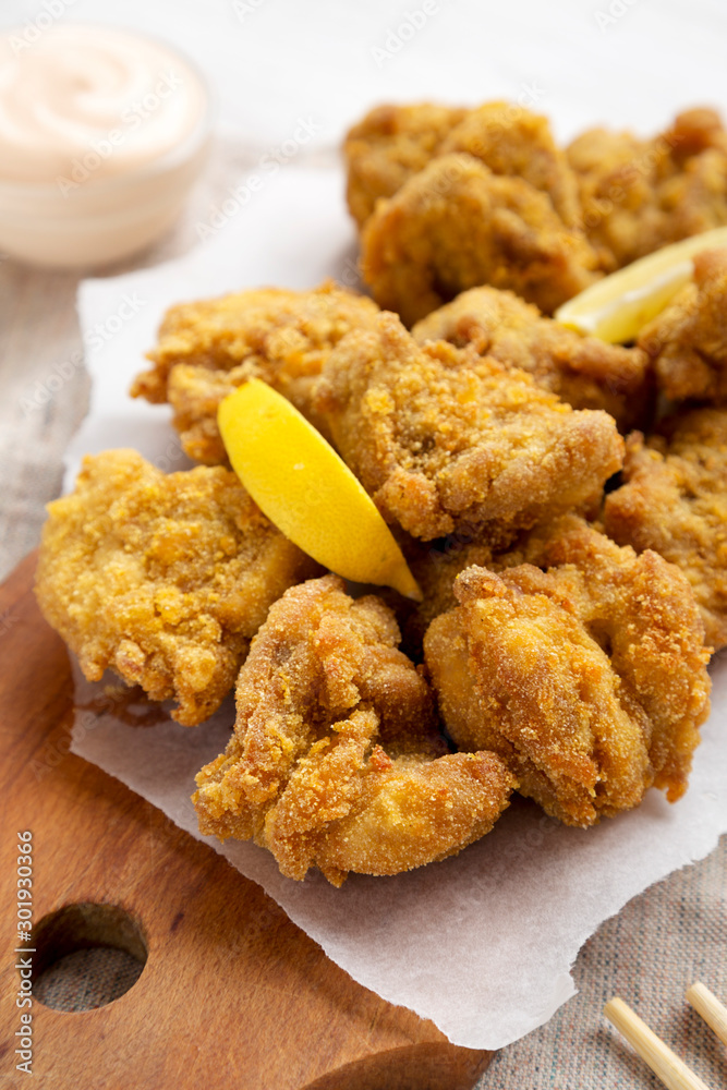 Homemade traditional japanese fried chicken Karaage on a rustic wooden board, side view. Close-up. Homemade traditional japanese fried chicken Karaage on a rustic wooden board, side view. Close-up.