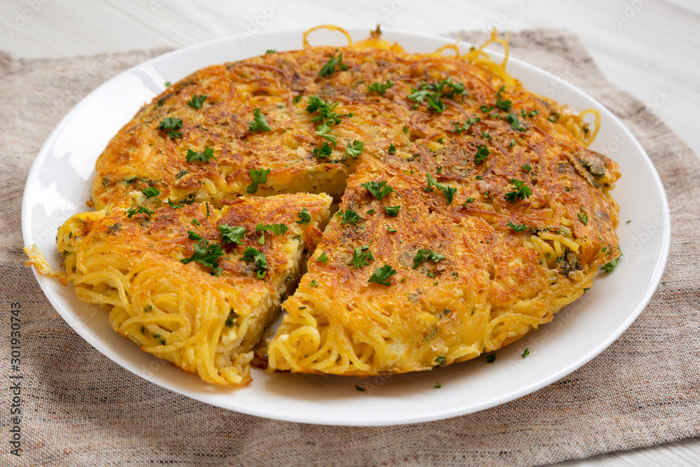 Homemade spaghetti omelette on a white plate, side view. Close-up. Homemade spaghetti omelette on a white plate, side view. Close-up.
