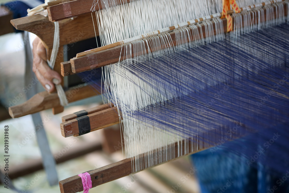 Weaving. Woman hand weaving on manual loom. Fabric handmade. Homespun fabric process. The process of fabric weaving in vintage weaver machine. Selective focus.