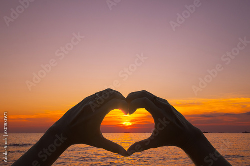 "Love sign" hand heart symbol in afternoon sunset ocean sea sky.