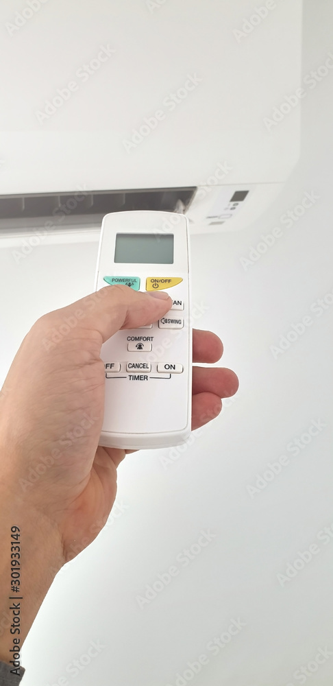 Modern airconditioner unit with a hand holding a remote. Modern airconditioner unit with a hand holding a remote.