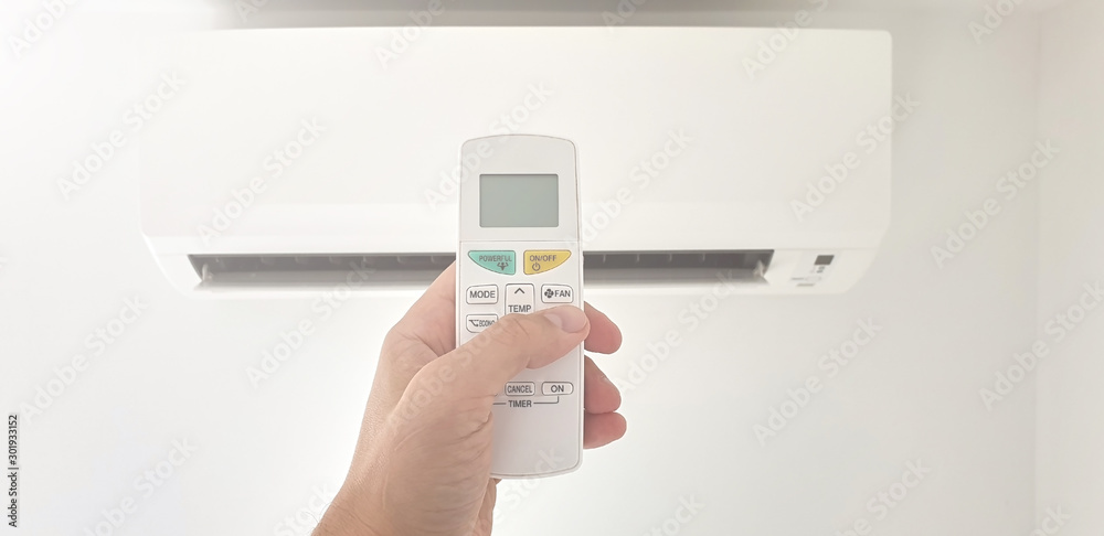 Modern airconditioner unit with a hand holding a remote. Modern airconditioner unit with a hand holding a remote.
