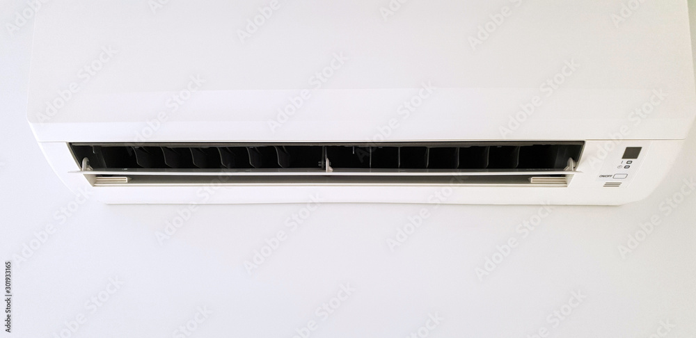 Modern air condition unit on a white wall inside the living room. Modern air condition unit on a white wall inside the living room.