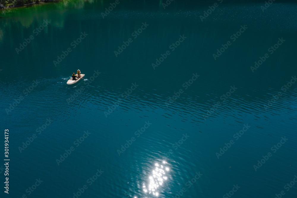 Boat on beautiful blue mountain lake, aerial view, tranquil landscape. Kolsay, Kazakstan