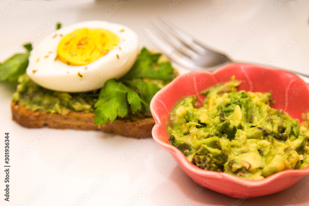 bowl with guacamole and guacamole toast and hard boiled egg with parsley bowl with guacamole and guacamole toast and hard boiled egg with parsley