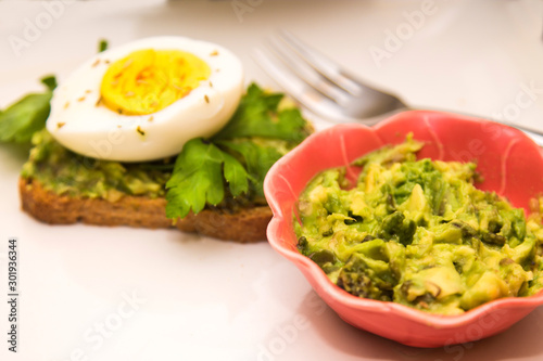 bowl with guacamole and guacamole toast and hard boiled egg with parsley