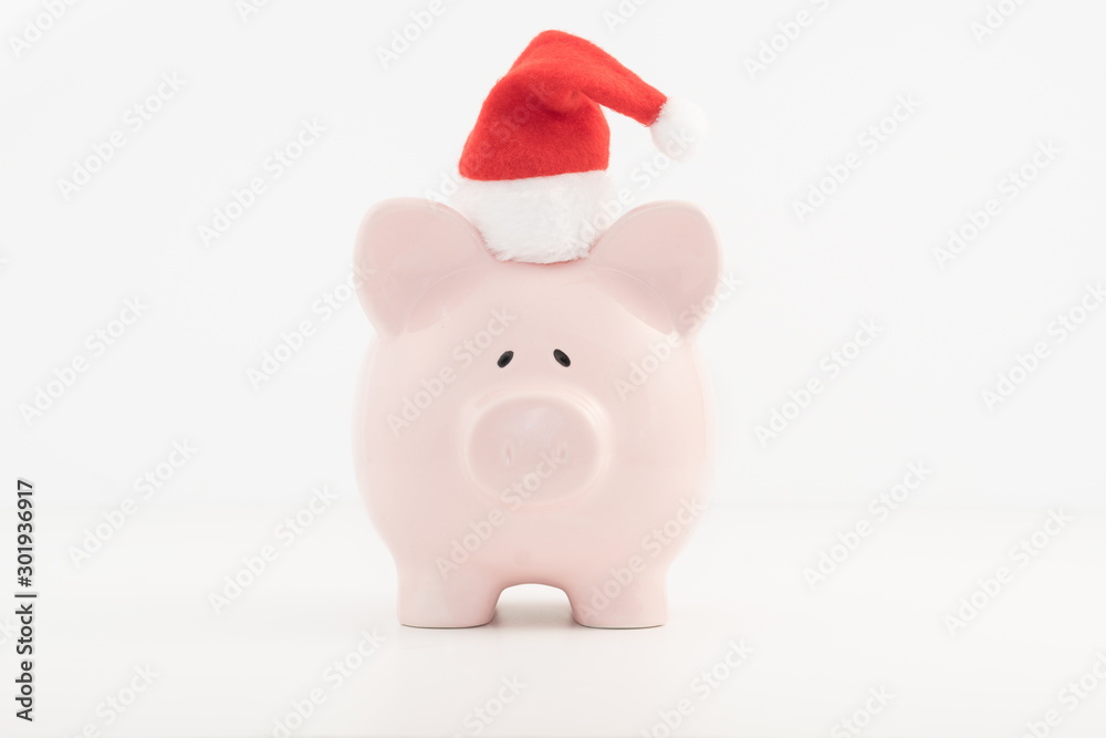 Concept image for savings planning featuring a pink piggy bank wearing a red Santa hat. Concept image for savings planning featuring a pink piggy bank wearing a red Santa hat.