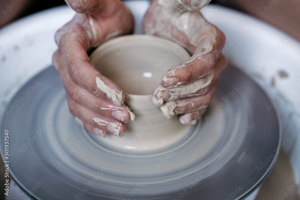 Female potter hands working with clay in workshop. White desk on background Female potter hands working with clay in workshop. White desk on background