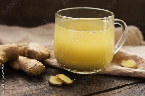 Cup of ginger tea on wooden background