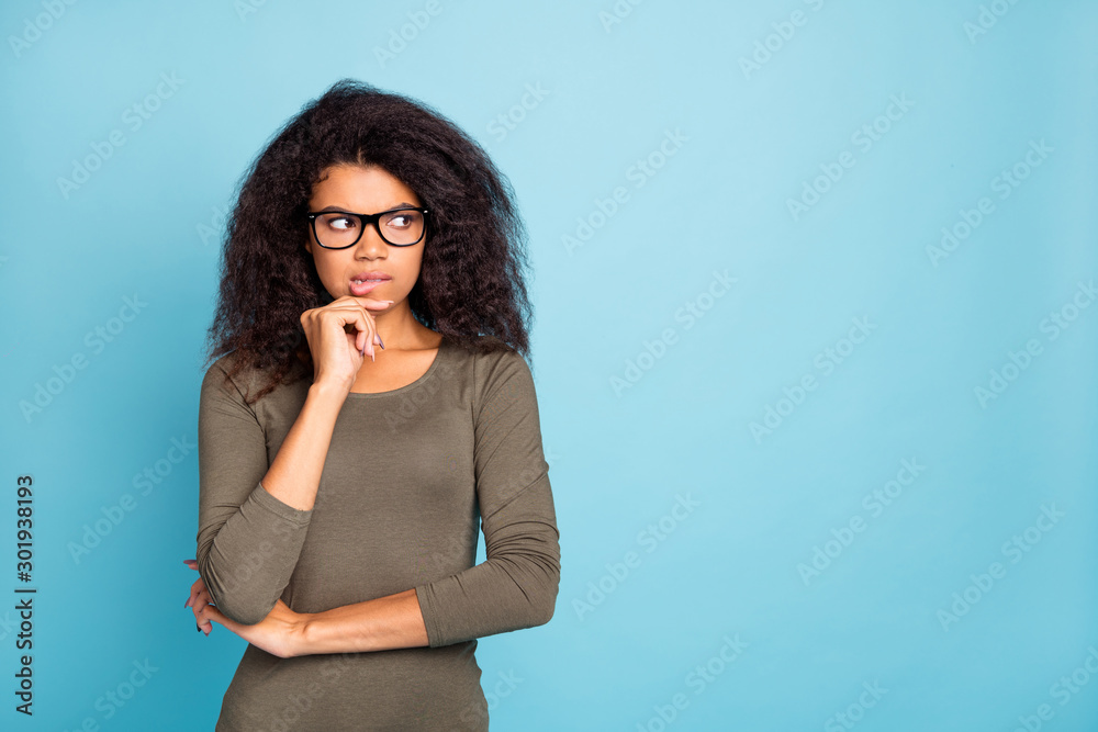 Portrait of minded pensive interested dark skin girl think have horrible thoughts feel fear frightened emotion bite lips look wear stylish outfit isolated over blue color background Portrait of minded pensive interested dark skin girl think have horrible thoughts feel fear frightened emotion bite lips look wear stylish outfit isolated over blue color background
