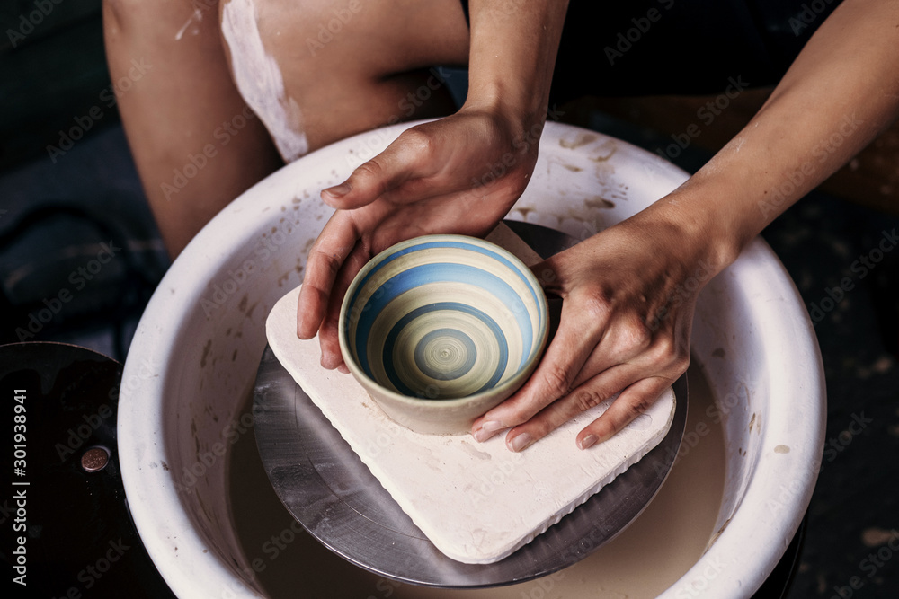 Fototapeta premium Female potter hands working with clay in workshop. White desk on background