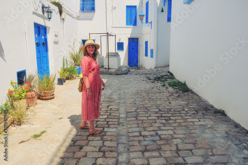 Girl stands in the courtyard with blue windows and doors with Arabic ornaments. Texture of Islamic symbols in Sidi Bou said, Tunisia, Africa © Андрей Журавлев