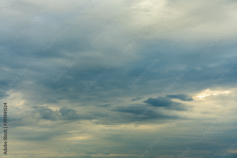 Overcast sky with thick gray and white clouds and a setting sun