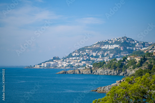 View of the city of Roses and the bay on a bright sunny day from the surrounding mountains. Vacation on the sea, hiking, active healthy lifestyle. Catalonia, Spain.