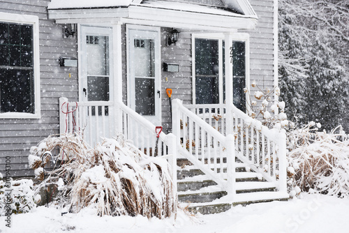 a small cozy house covered with snow during the snowfall. The atmosphere of winter comfort and weather. photo