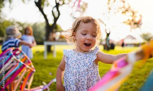 Photography A front view of small girl on birthday party outdoors in garden in summer