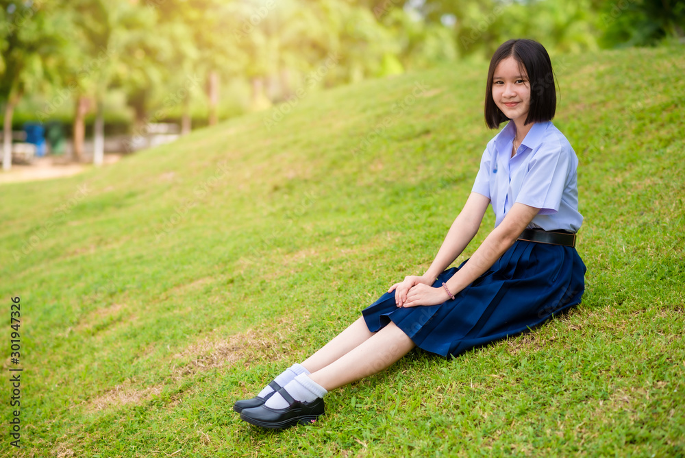 The smiling Asian high school female student in white uniform is smiling on the lawn. The smiling Asian high school female student in white uniform is smiling on the lawn.