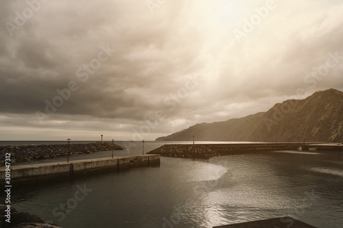 Wallpaper Mural Wall separating Atlantic ocean from the area of a small port. Mountains in the background. Sao Miguel, Azores Islands, Portugal Torontodigital.ca
