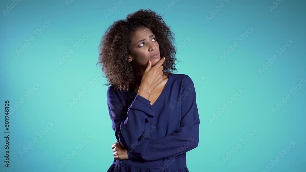Smiling african girl showing eureka gesture. Portrait of young thinking pondering business woman having idea moment pointing finger up on blue background Smiling african girl showing eureka gesture. Portrait of young thinking pondering business woman having idea moment pointing finger up on blue background