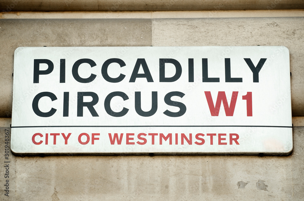 Piccadilly Circus street sign hangs from traditionally English stone building in the City of Westminster, London, UK