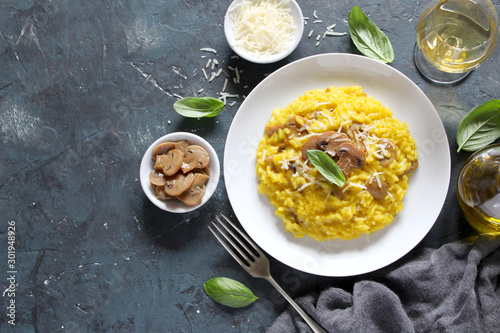Traditional Italian risotto with mushrooms, saffron and parmesan cheese on white wooden background. Top view with copy space. photo