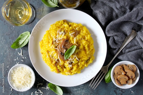 Traditional Italian risotto with mushrooms, saffron and parmesan cheese on white wooden background. Top view with copy space. photo