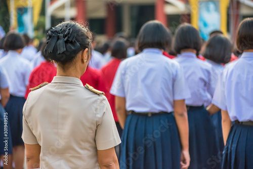 The high school teachers in Thai government teacher uniform are standing among students, Thailand, southeast Asia.